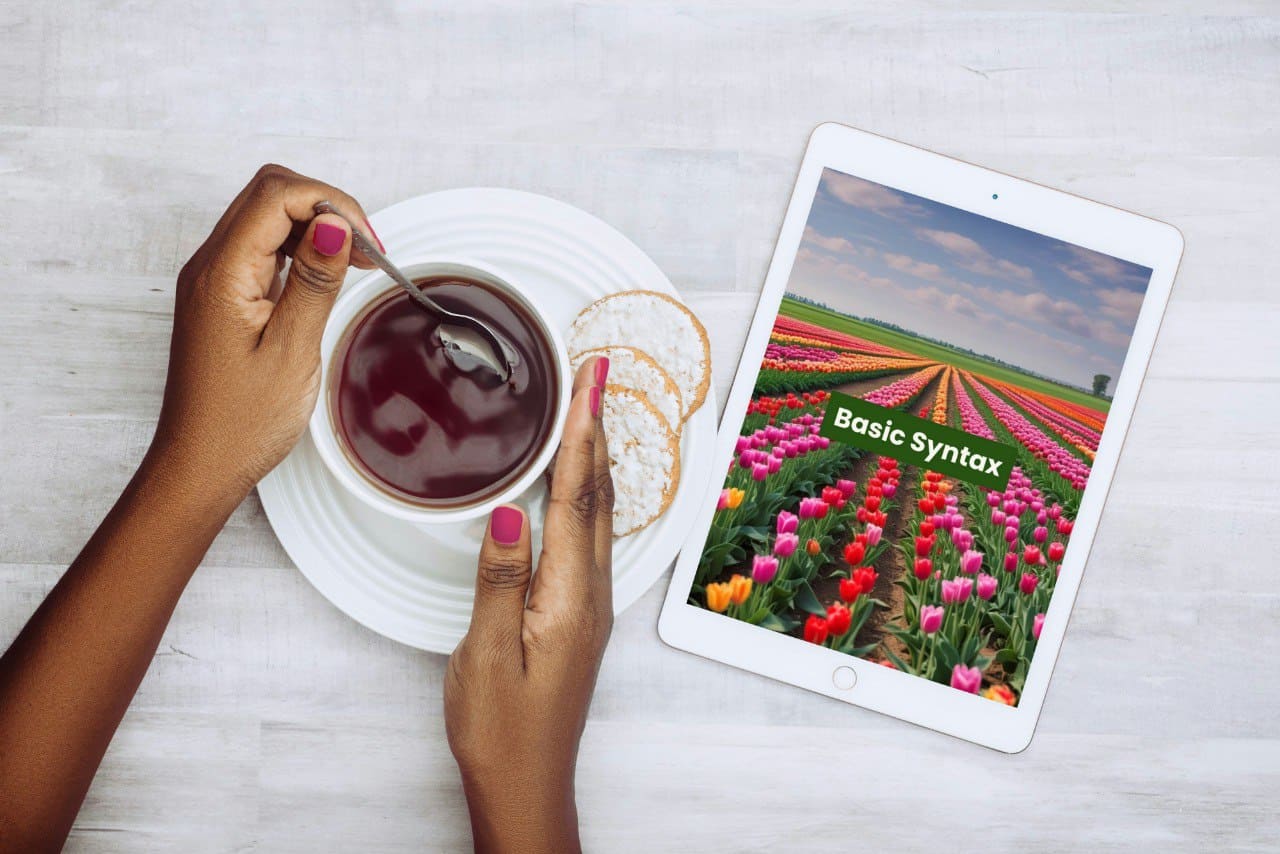 Person holding a cup of tea with a tablet displaying a flower C++ course cover and 'Basic Syntax' text.